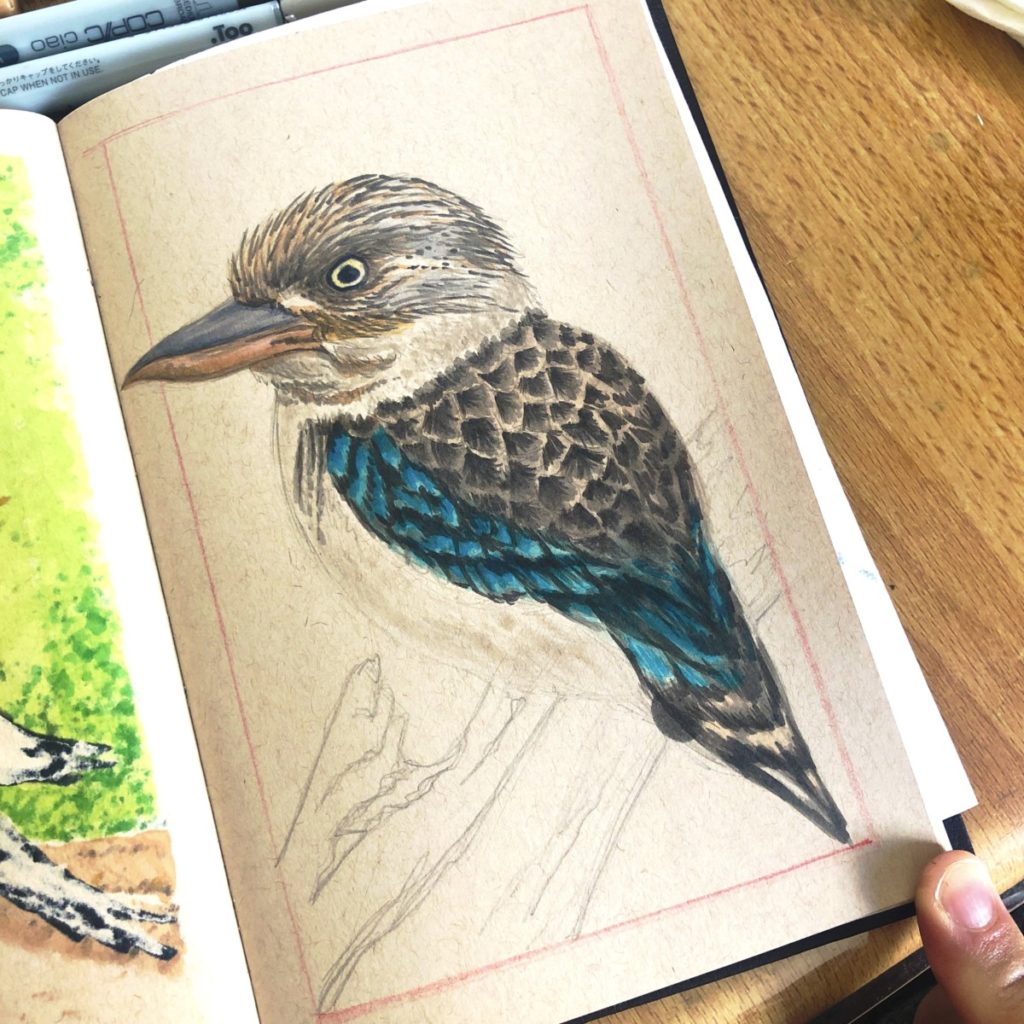 Kookaburra Illustration process shot. Working on filling in feathers. Copic markers & Posca pens on tan tones Strathmore Sketchbook.